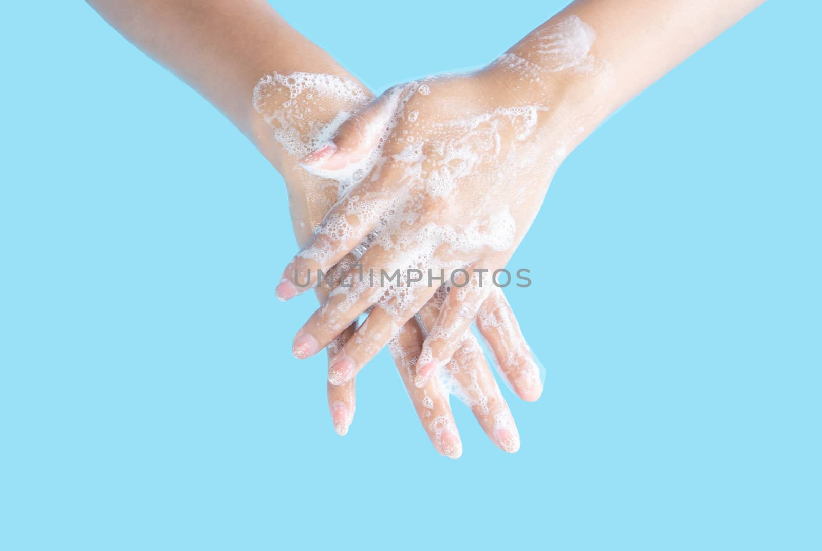 Closeup woman's hand washing with soap on blue background, health care concept