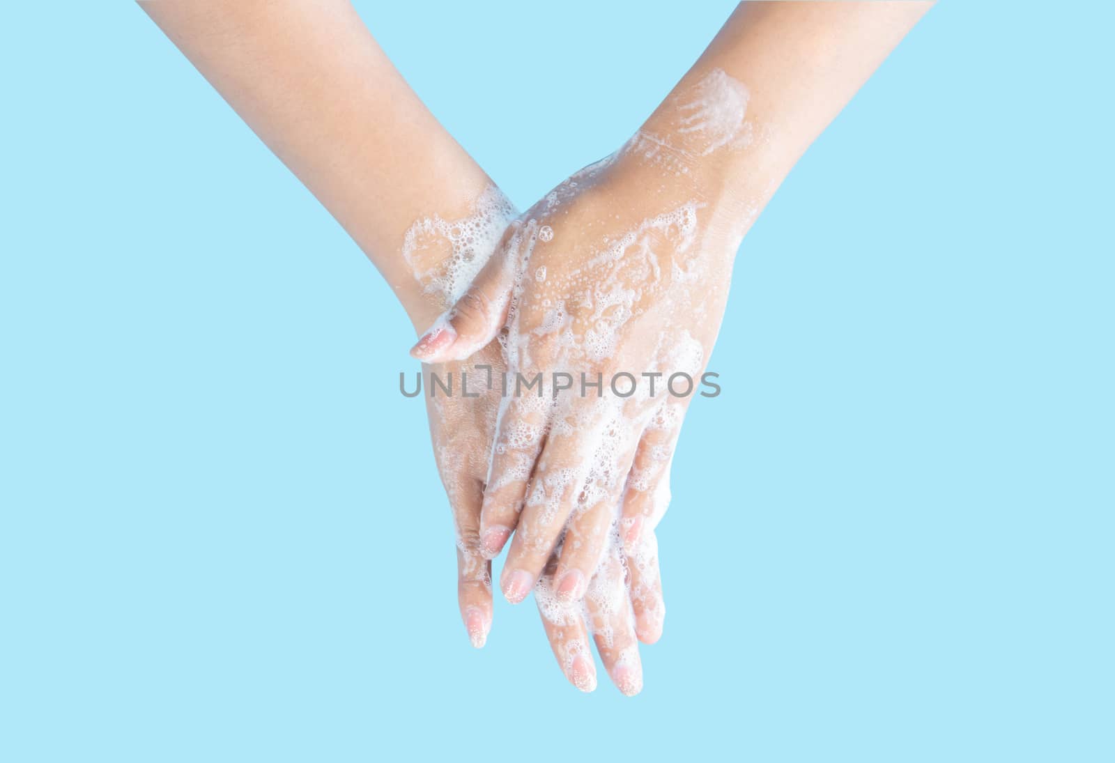 Closeup woman's hand washing with soap on blue background, health care concept