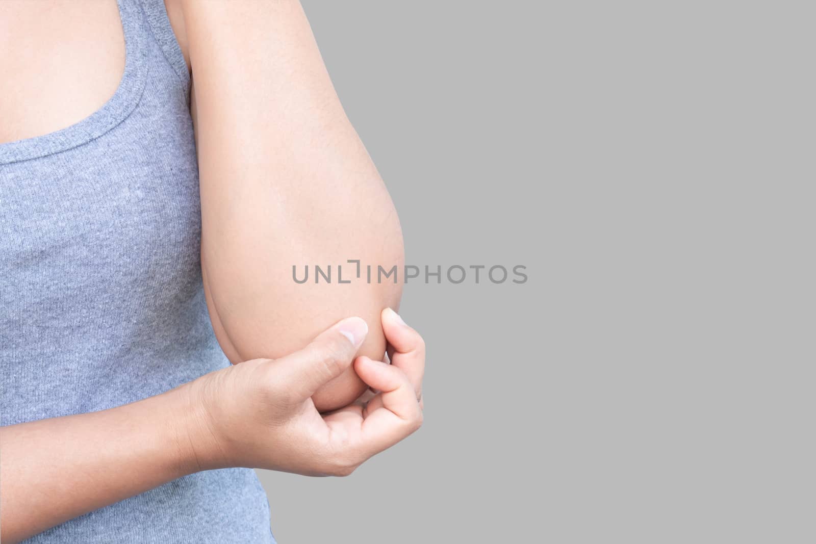 Closeup woman hand holding elbow with pain on grey background, health care and medical concept