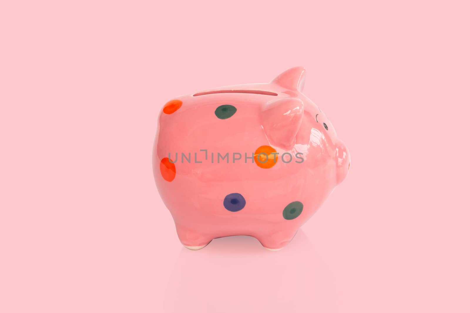 Pink ceramic piggy bank on pink background, saving money concept