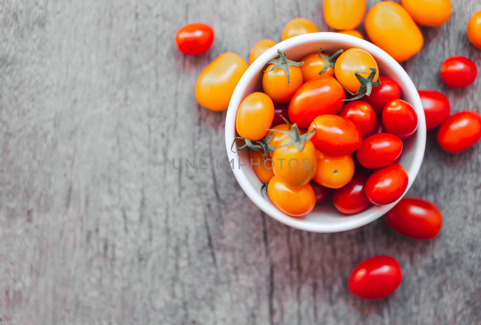 Top view Red cherry tomatoes in white ceramic bowl on old wooden background, vintage tone