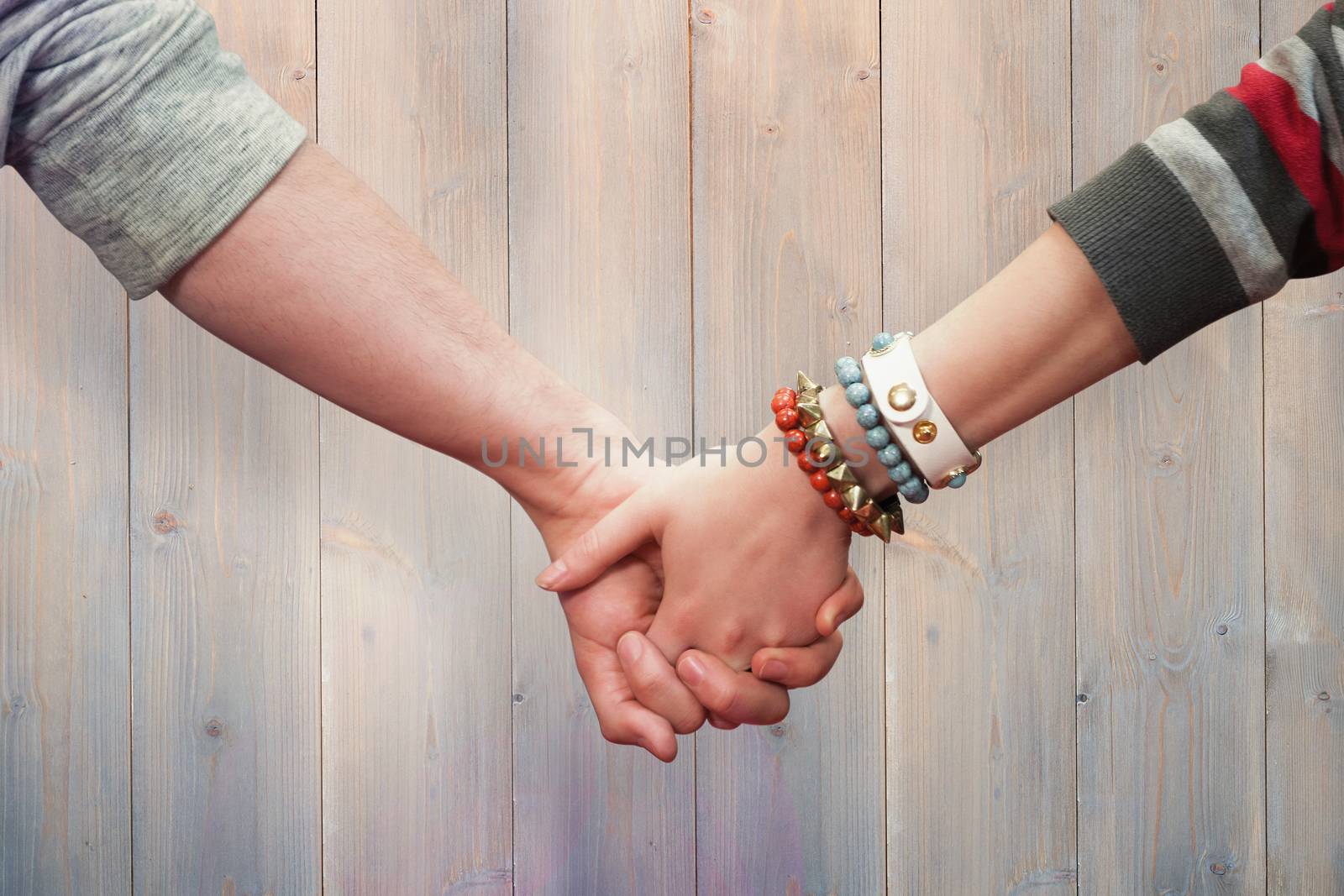 Students holding hands against pale grey wooden planks