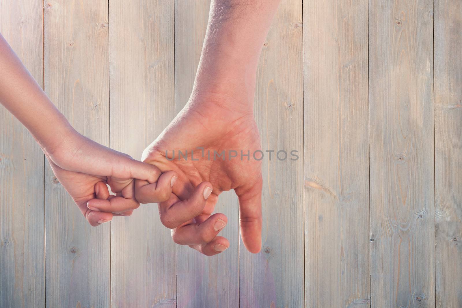 Loving young couple holding hands against pale grey wooden planks