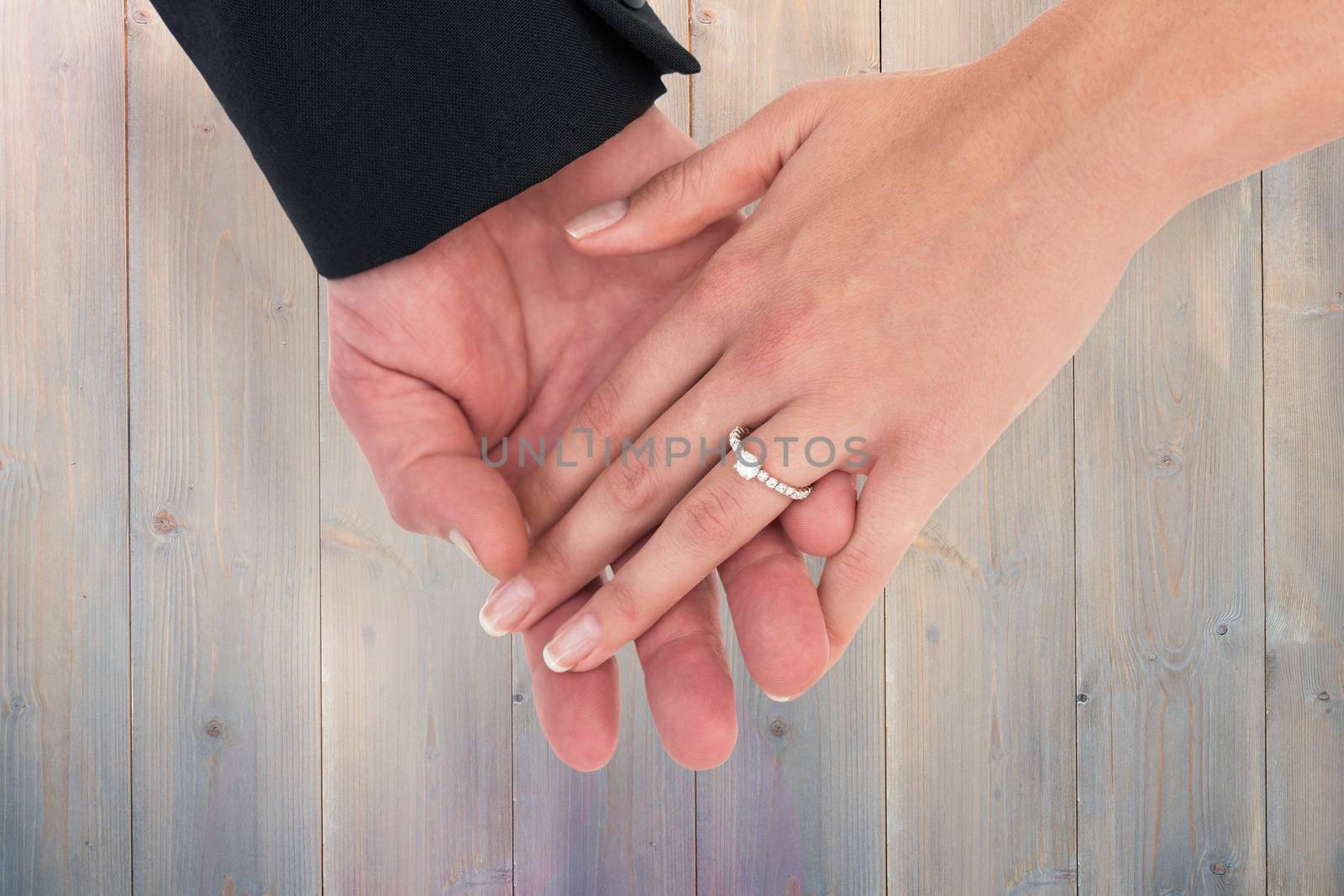 Close-up of bride and groom with hands together against pale grey wooden planks