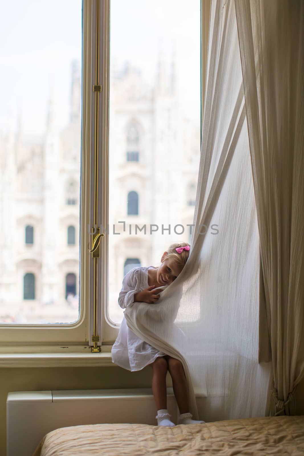 Adorable little girl looking out the window at Duomo, Milan, Italy by travnikovstudio