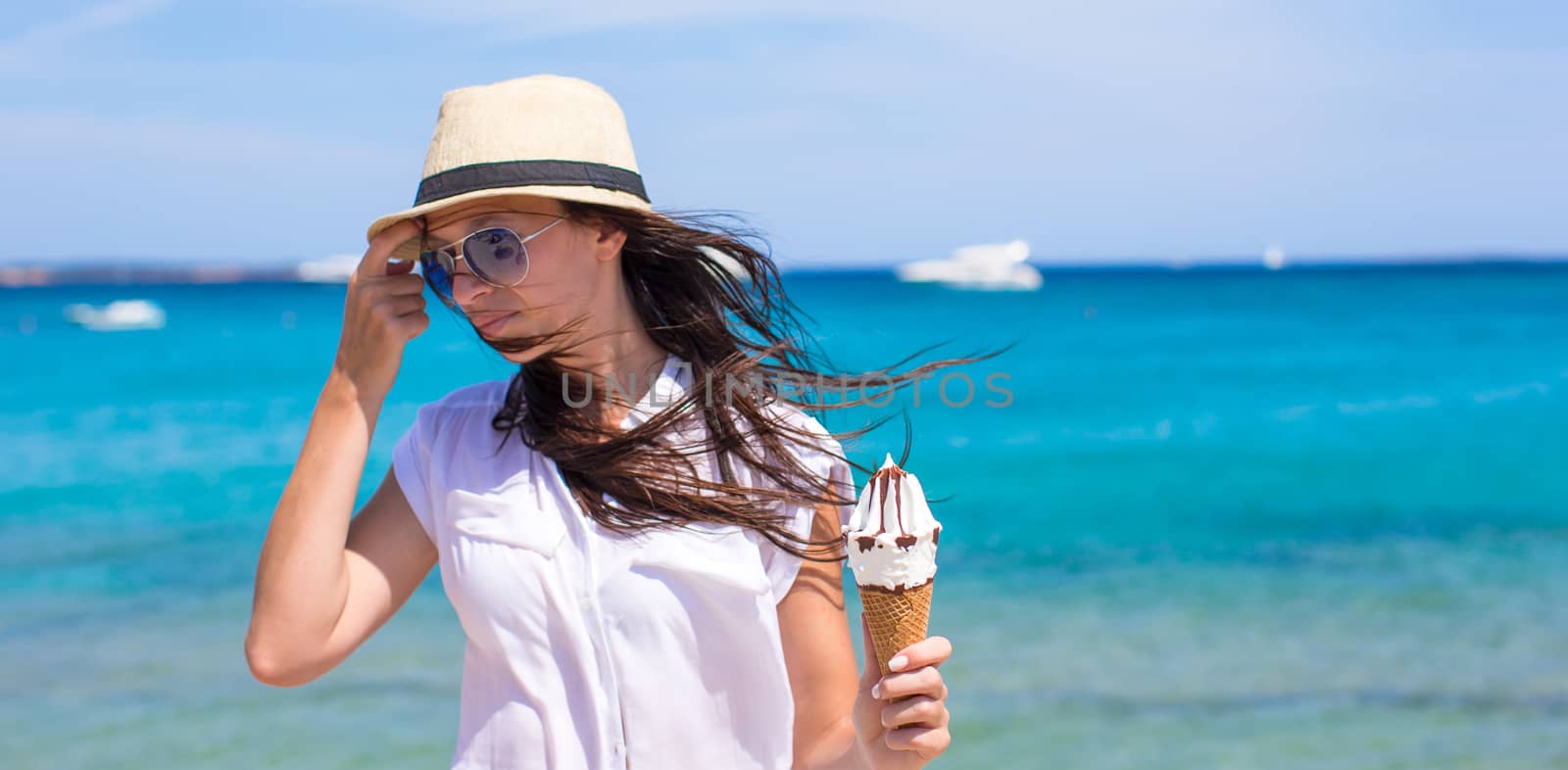 Adorable woman eating ice cream on tropical beach by travnikovstudio