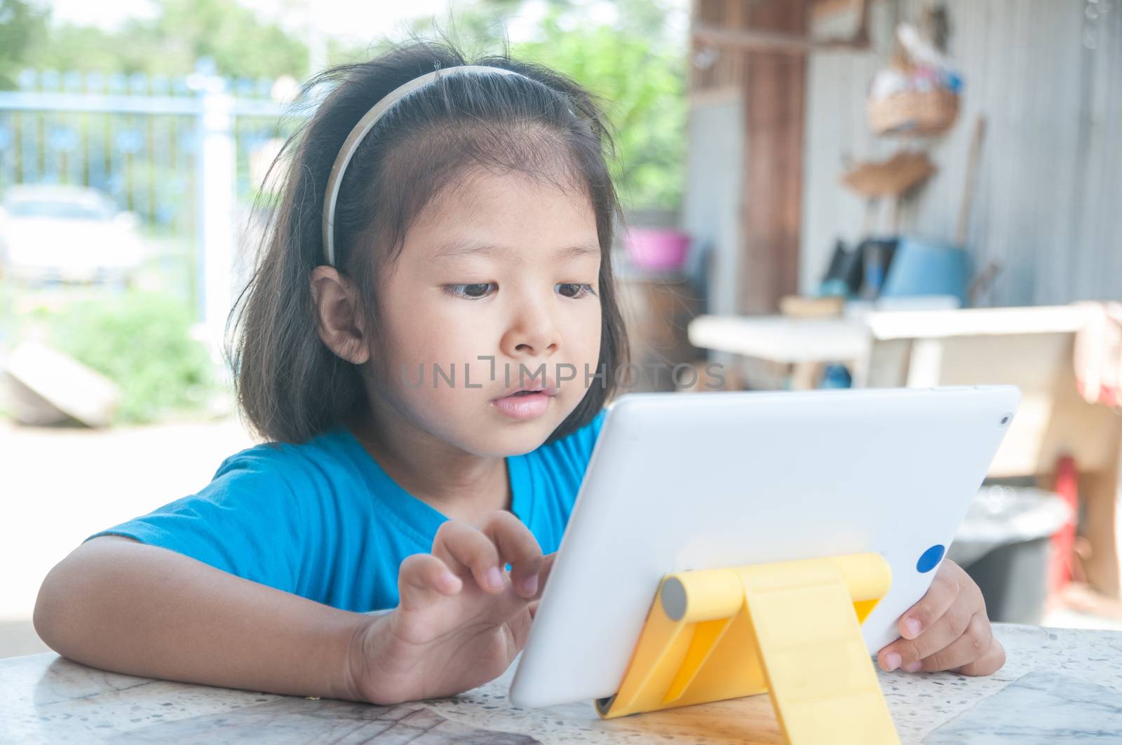 Asian Girl learning online course or playing game online on Digital Wireless Device or Tablet at home as Technology e-learning concept.