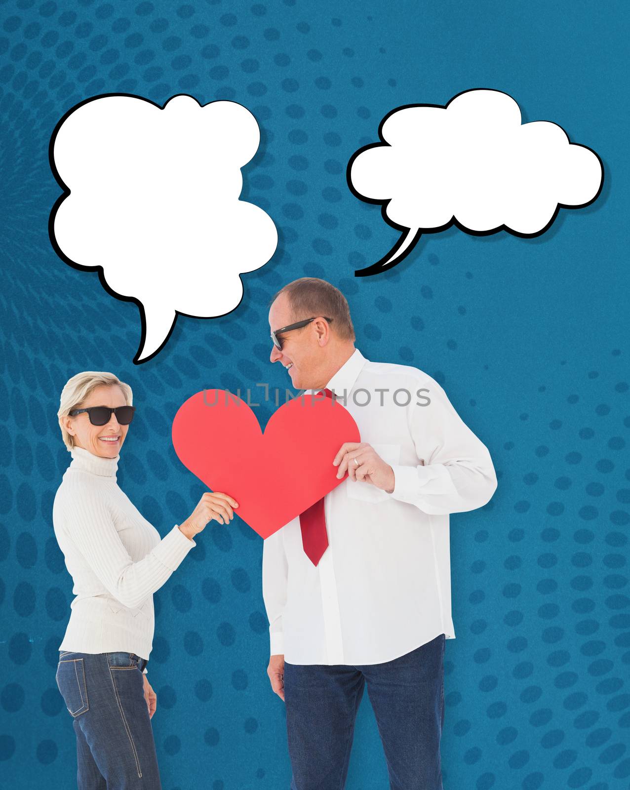 Older affectionate couple holding red heart shape against blue