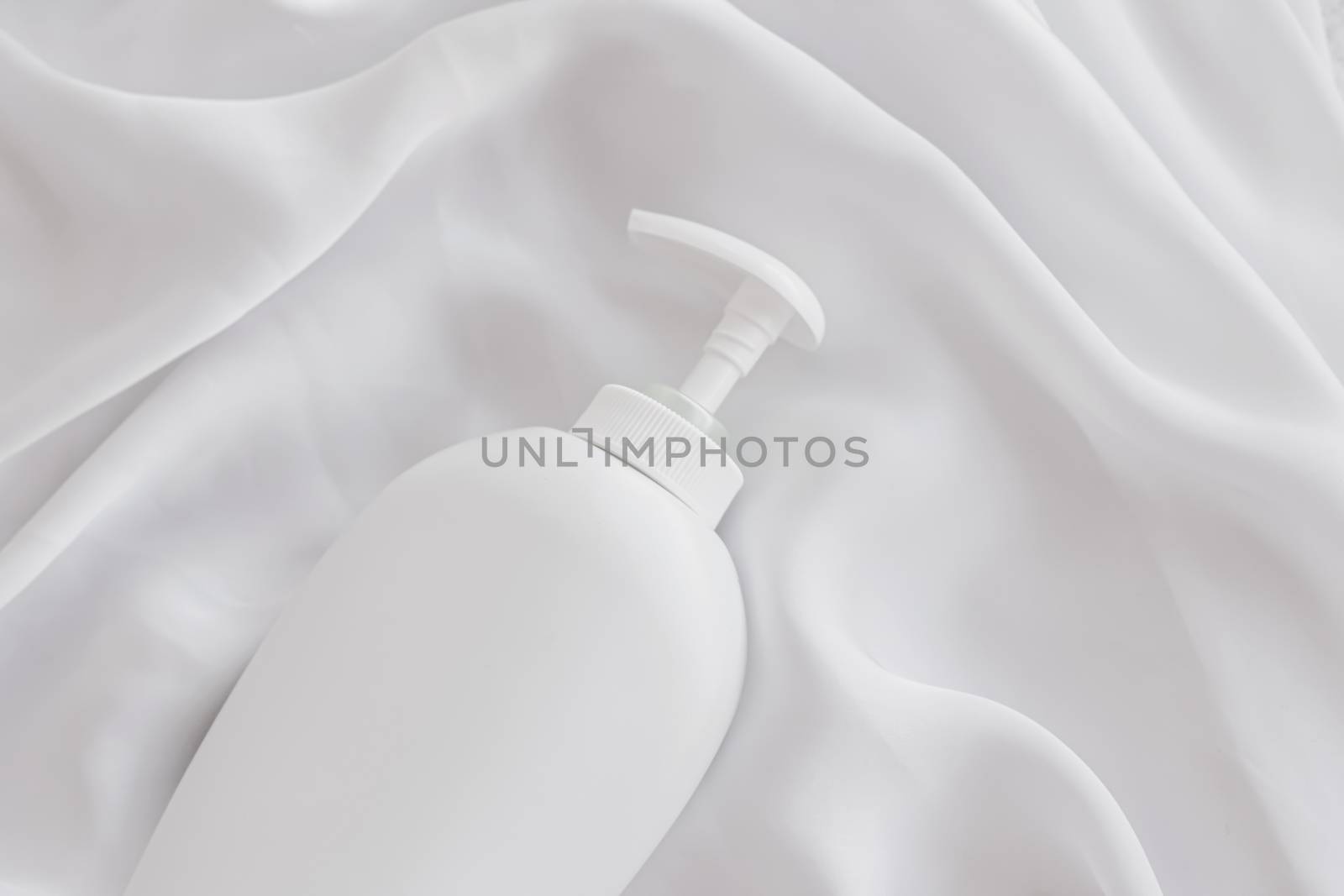 Blank label cosmetic container bottle as product mockup on white silk background by Anneleven