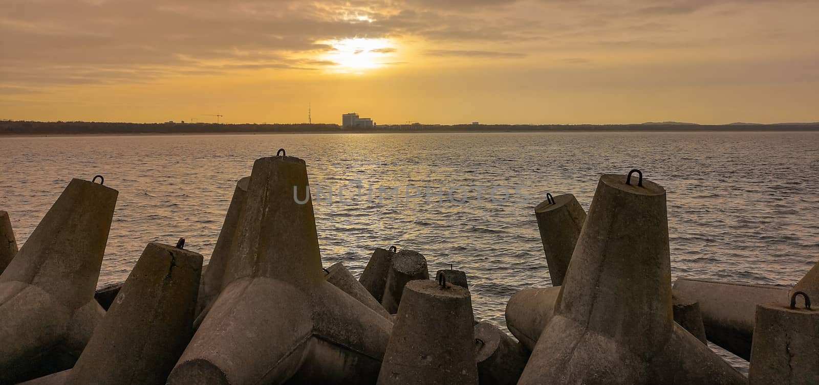 Sunset over baltic sea and coast of Swinoujscie city seen from breakwater by Wierzchu