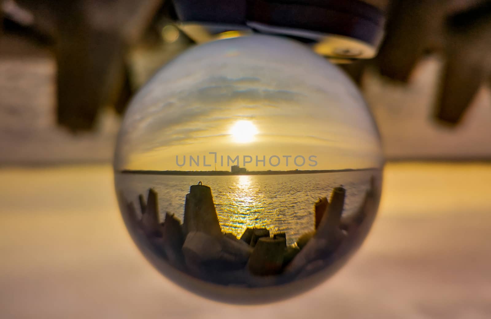 Sunset over baltic sea and coast of Swinoujscie city seen from breakwater in crystal glassball reflection by Wierzchu