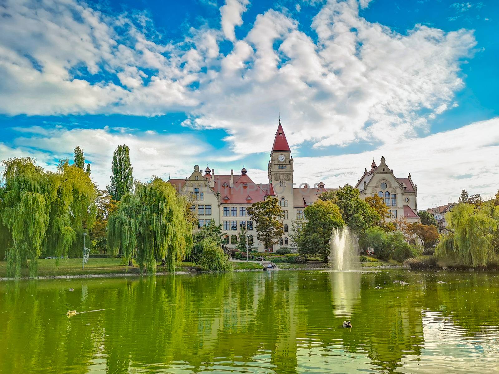 Lake in center of Wroclaw Tolpa Park with fountain in center with faculty of architecture of Wroclaw University