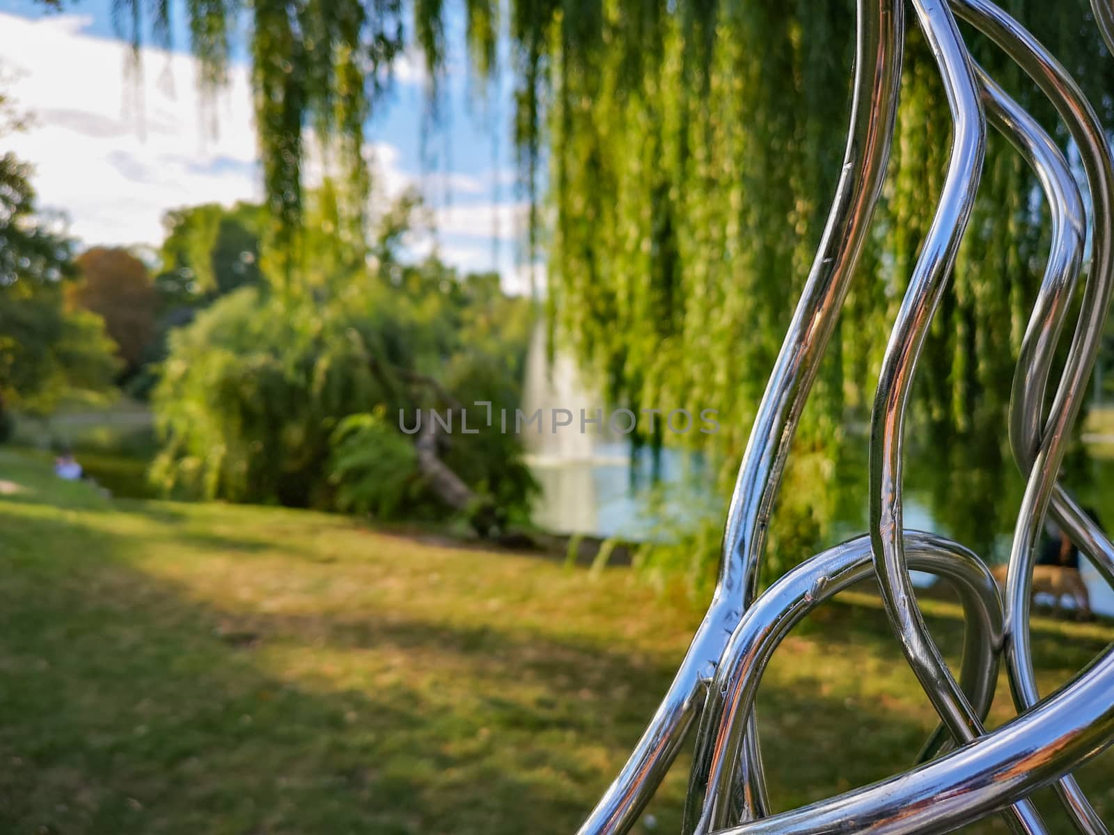 Part of chrome metal construction in park with colorful park in background