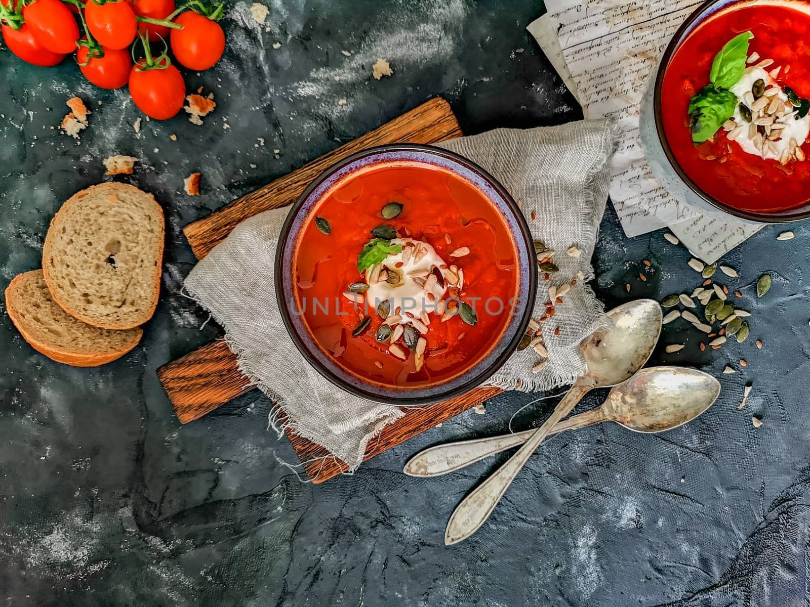 Flat lay of tomato soup with paper notes, bread, old spoons and cherry tomatoes by Wierzchu