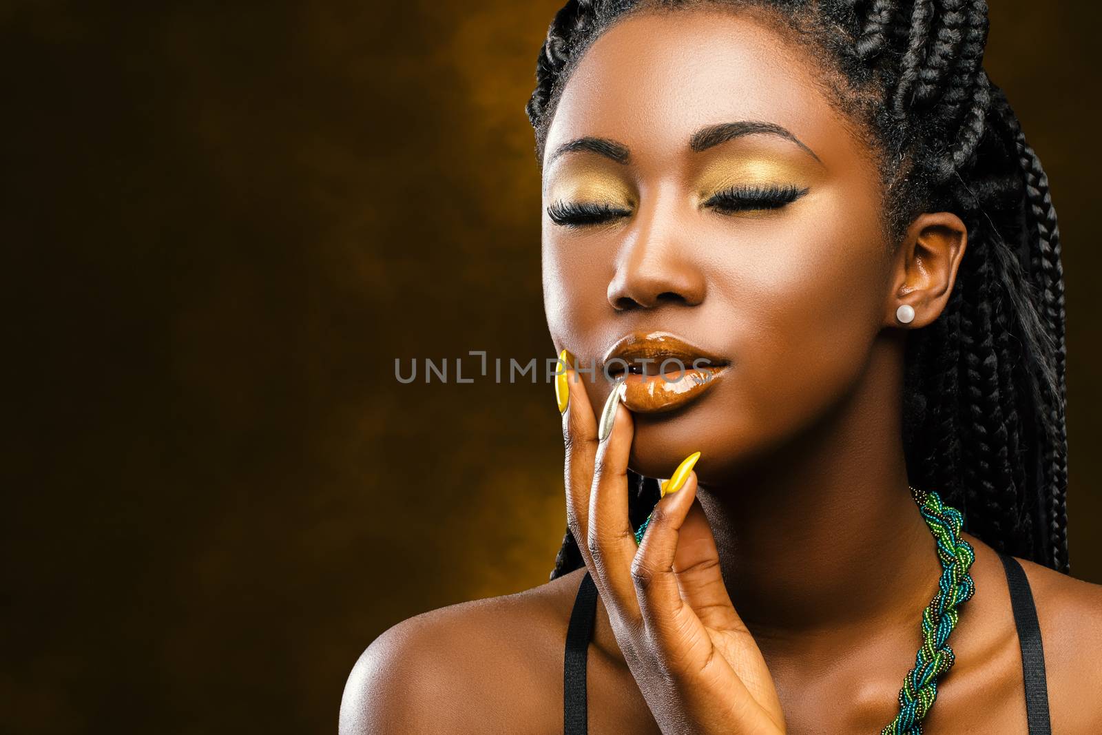Close up studio portrait of attractive young african woman with long braided hair.Girl with eyes closed touching face with hand.