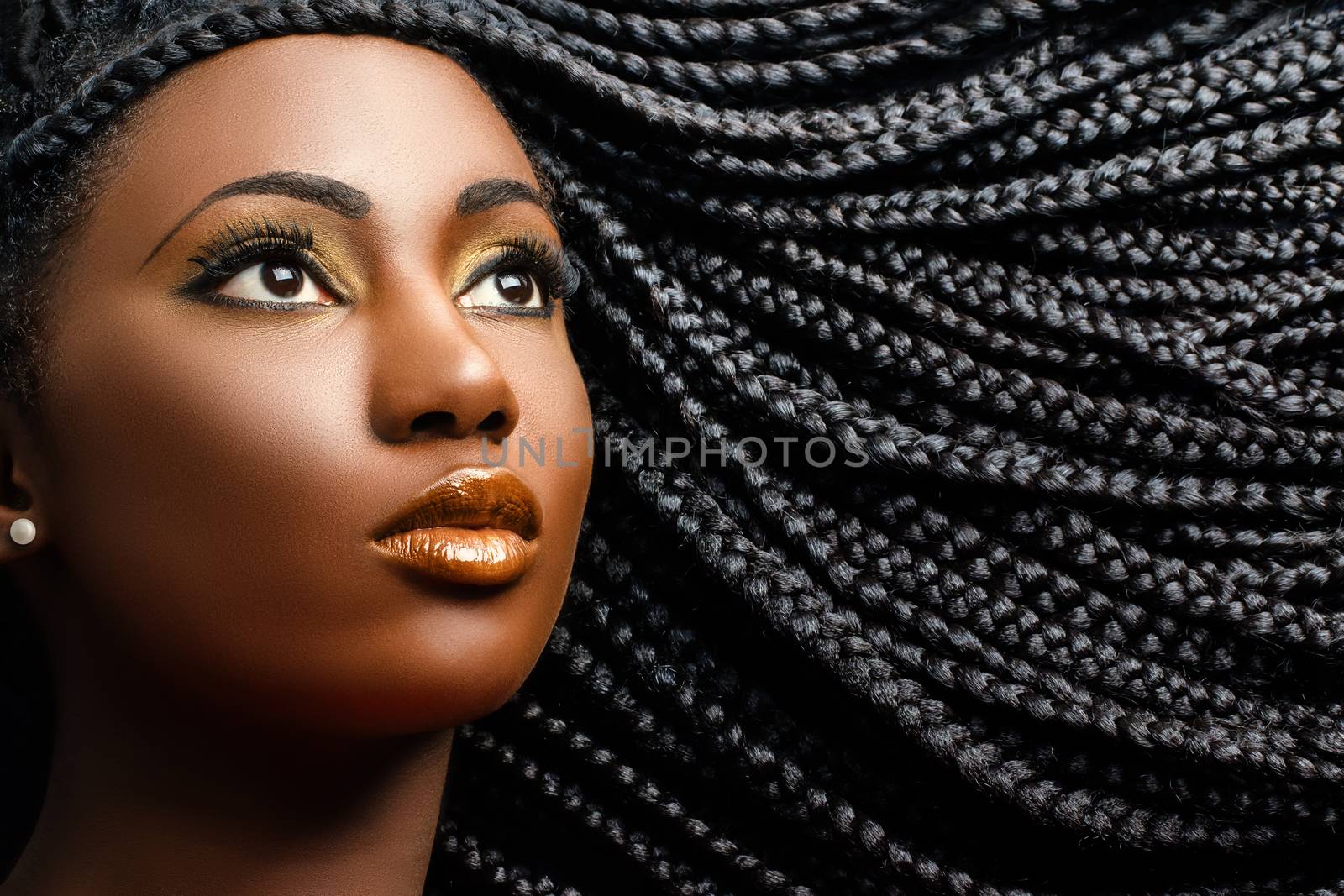 Close up cosmetic beauty portrait of african woman showing long black braided hairstyle.