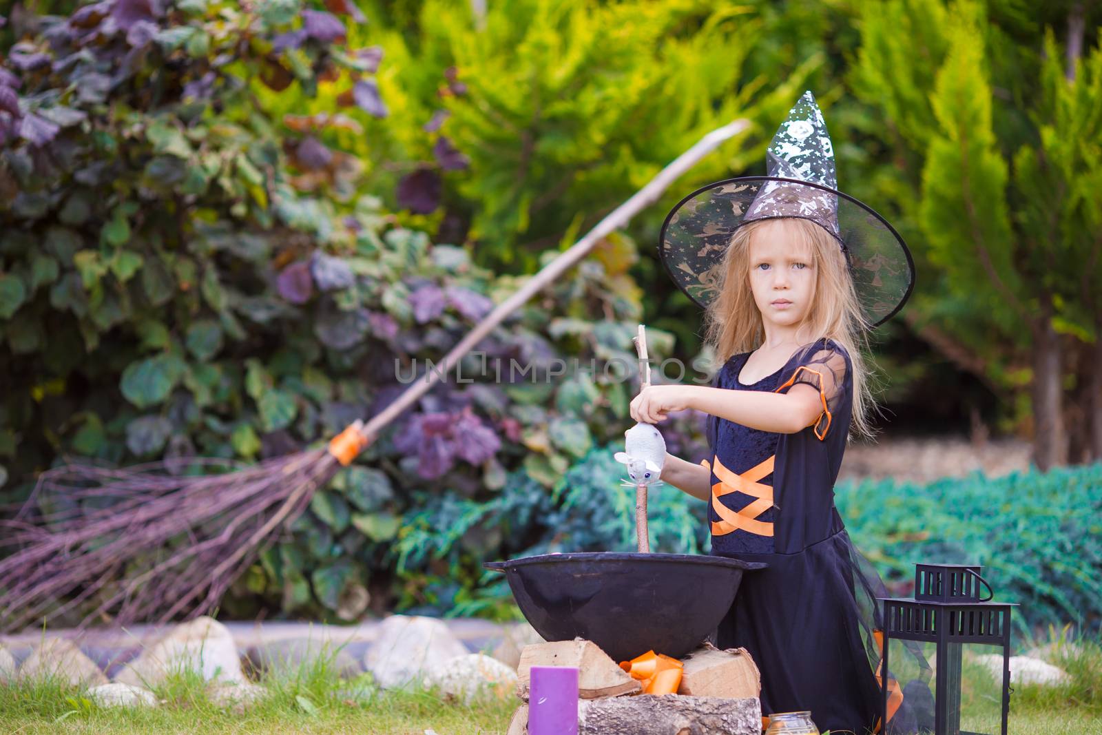 Adorable little girl wearing witch costume with broom on Halloween by travnikovstudio