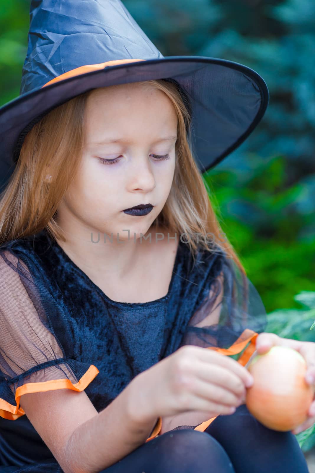 Adorable little girl wearing witch costume with broom on Halloween by travnikovstudio