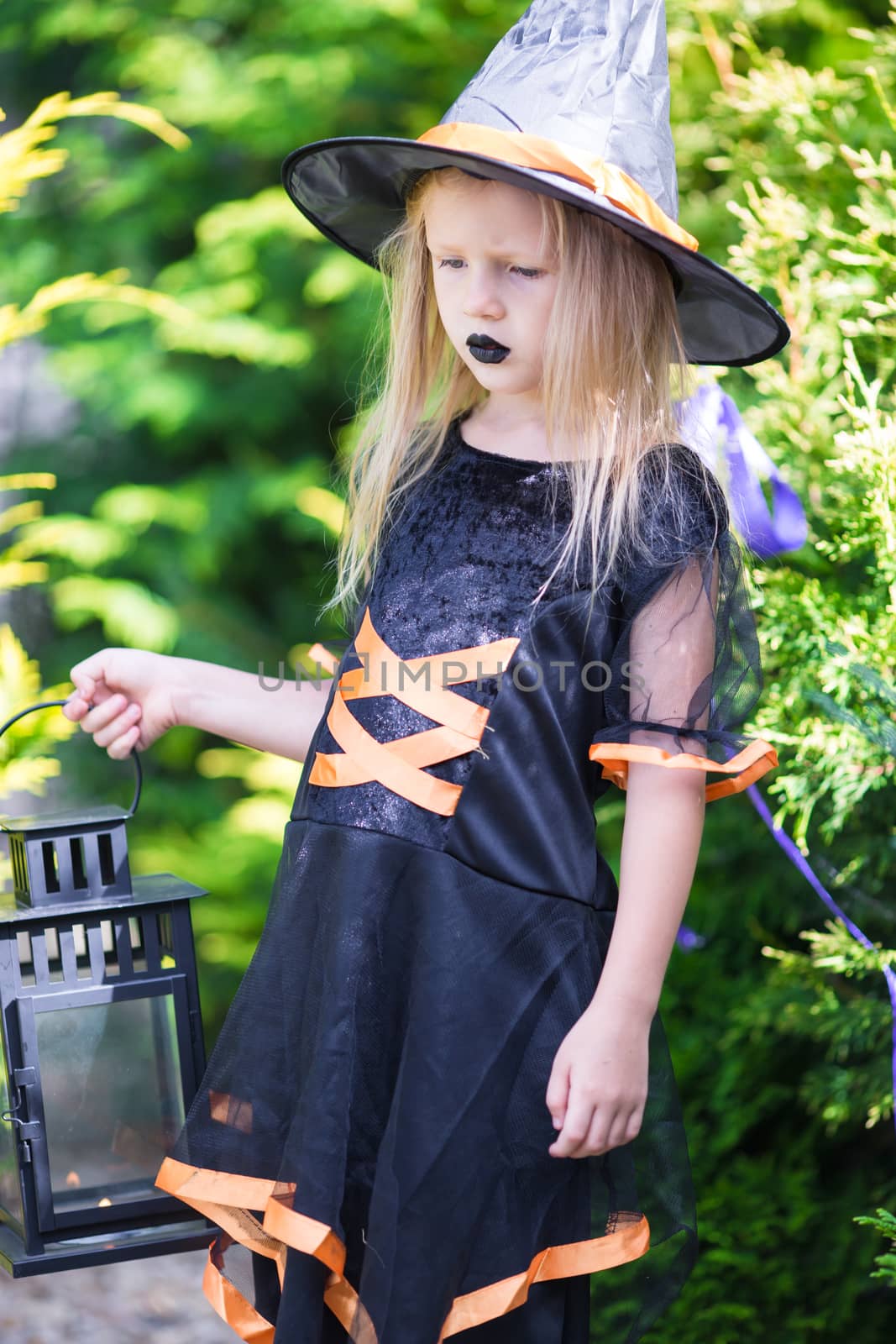 Adorable little girl wearing witch costume with broom on Halloween by travnikovstudio