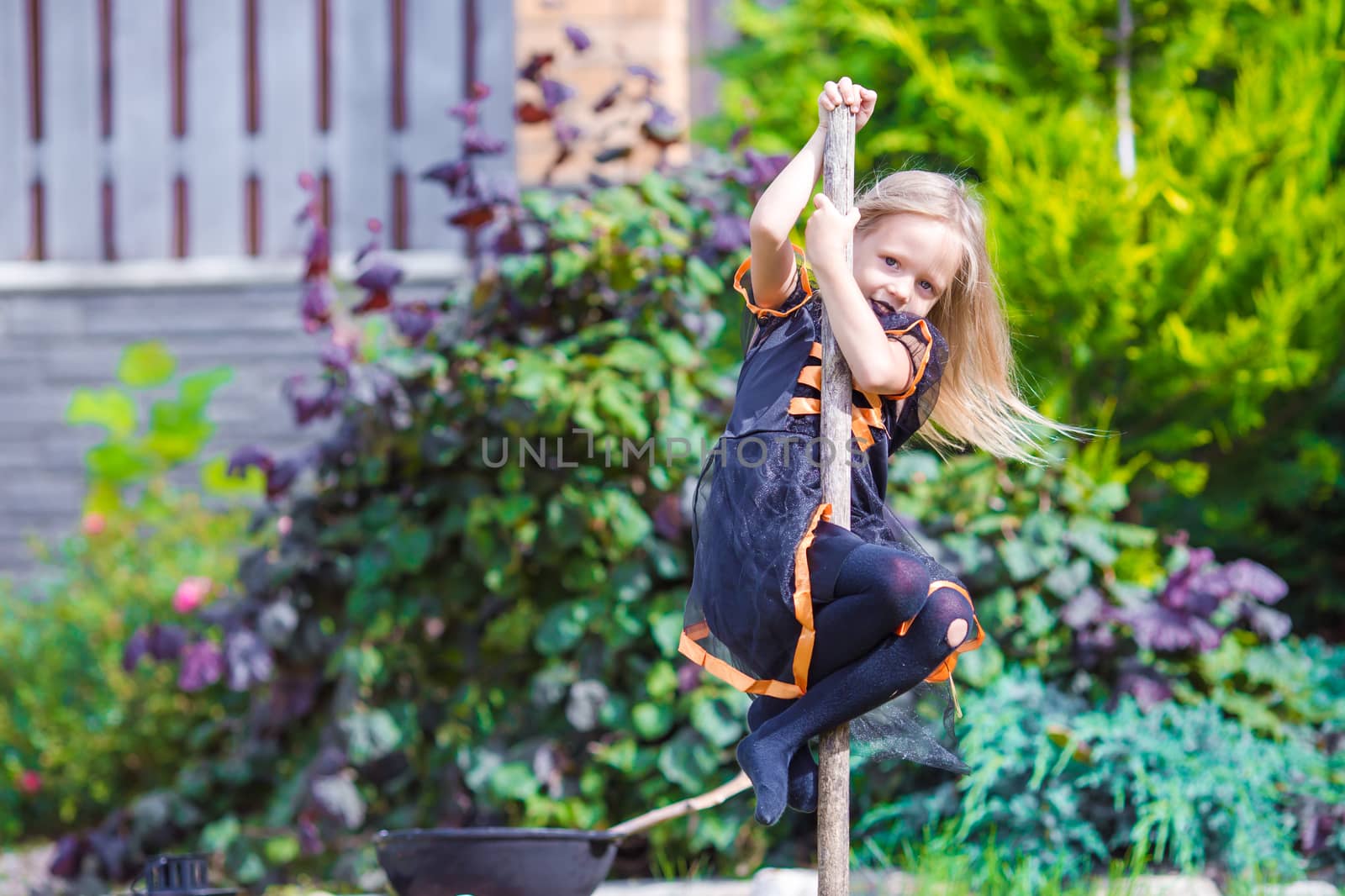 Little adorable girl in halloween costume having fun on a broomstick. Trick or treat. by travnikovstudio