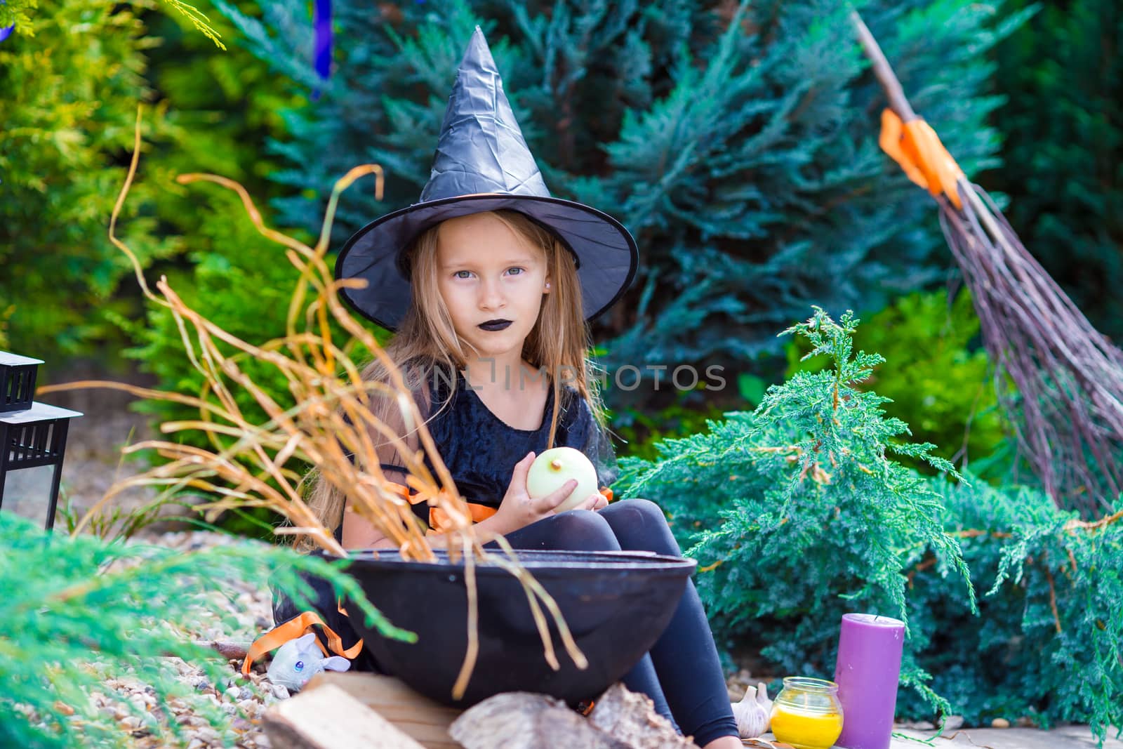 Adorable girl wearing witch costume on Halloween at autumn day by travnikovstudio