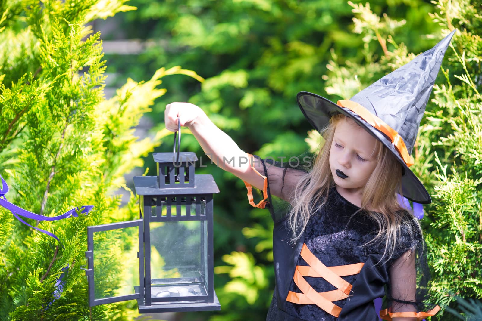 Adorable little girl wearing witch costume casting a spell on Halloween. Trick or treat. by travnikovstudio