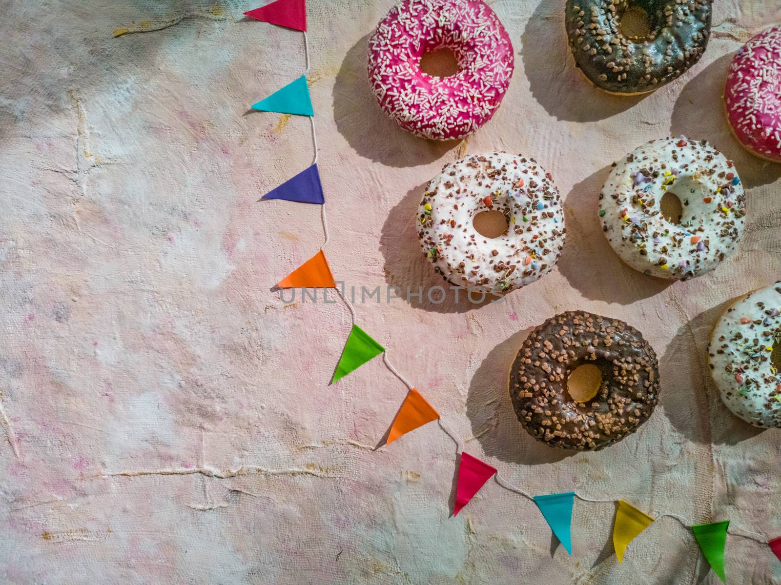 Flat lay of colorful donuts with colorful triangles on light fabric background