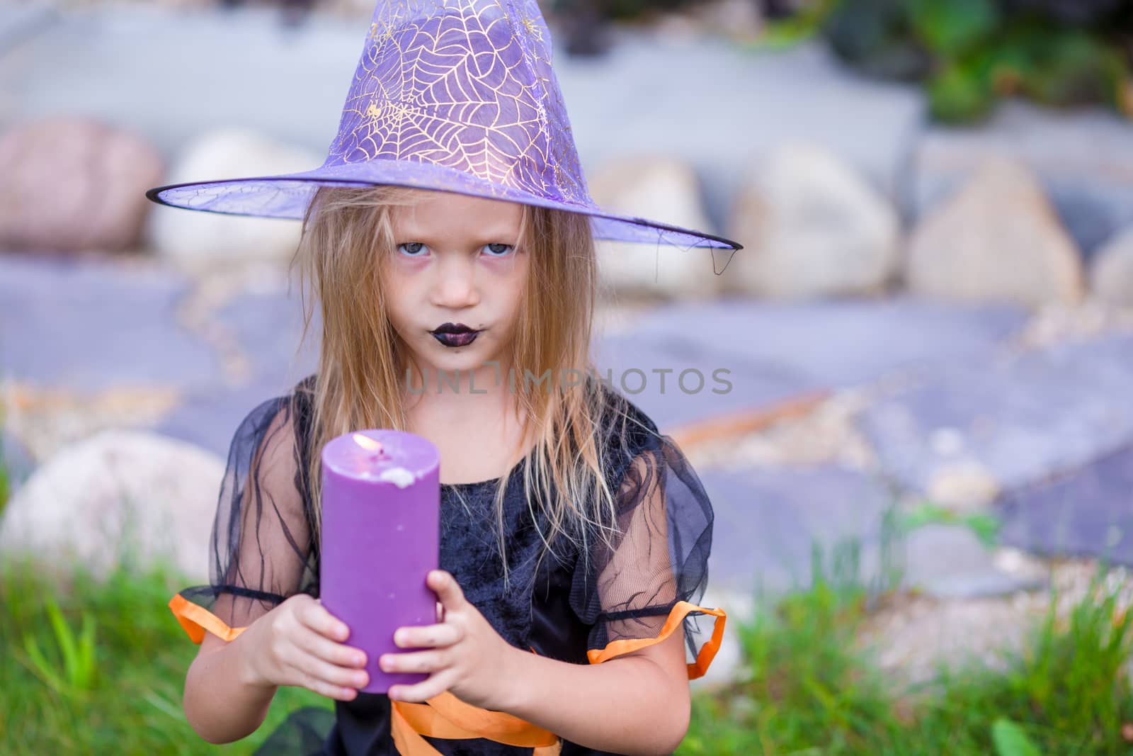 Halloween and adorable little girl with candle dressed as a witch by travnikovstudio