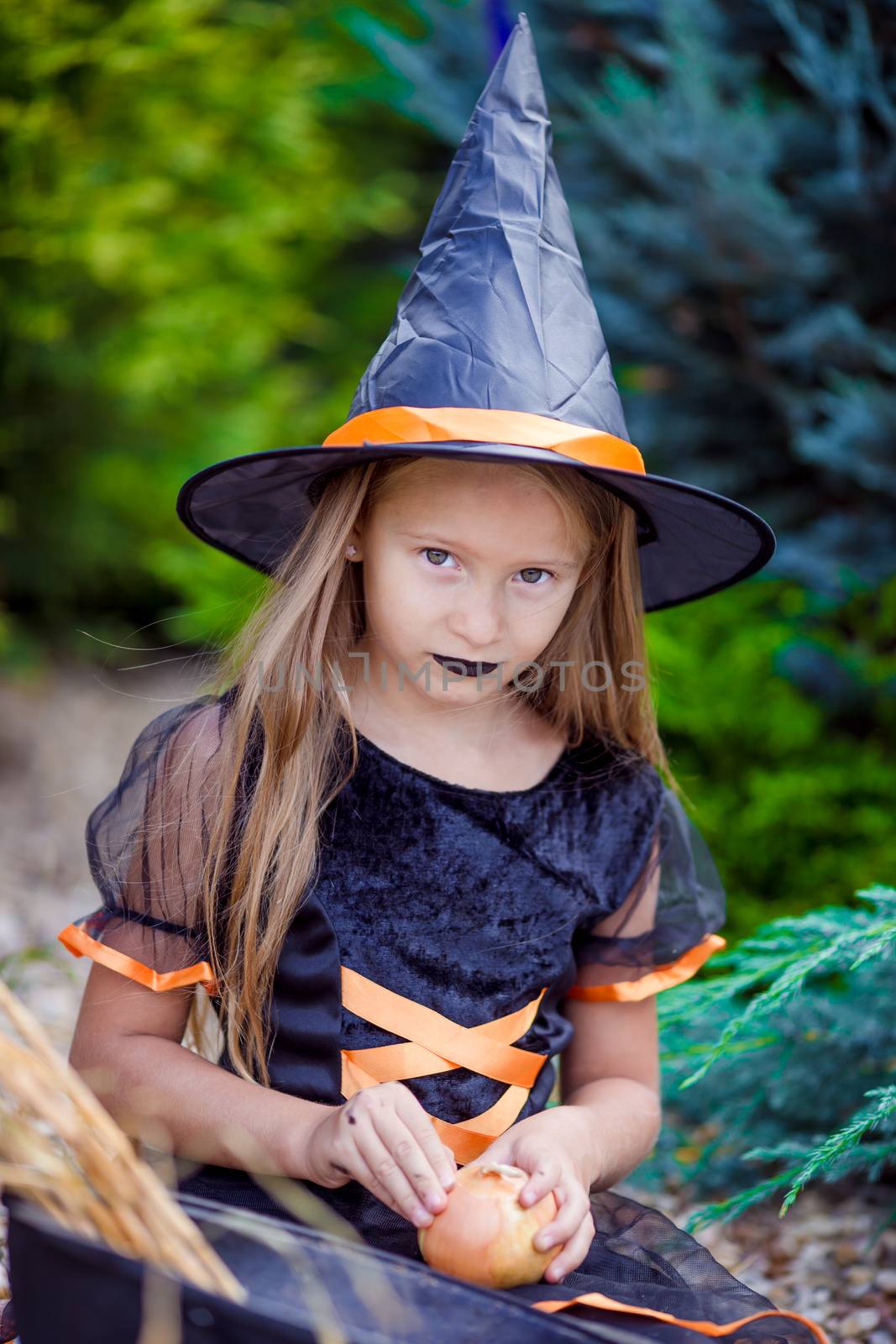 Portrait of cute little girl wearing witch costume with broom on Halloween by travnikovstudio