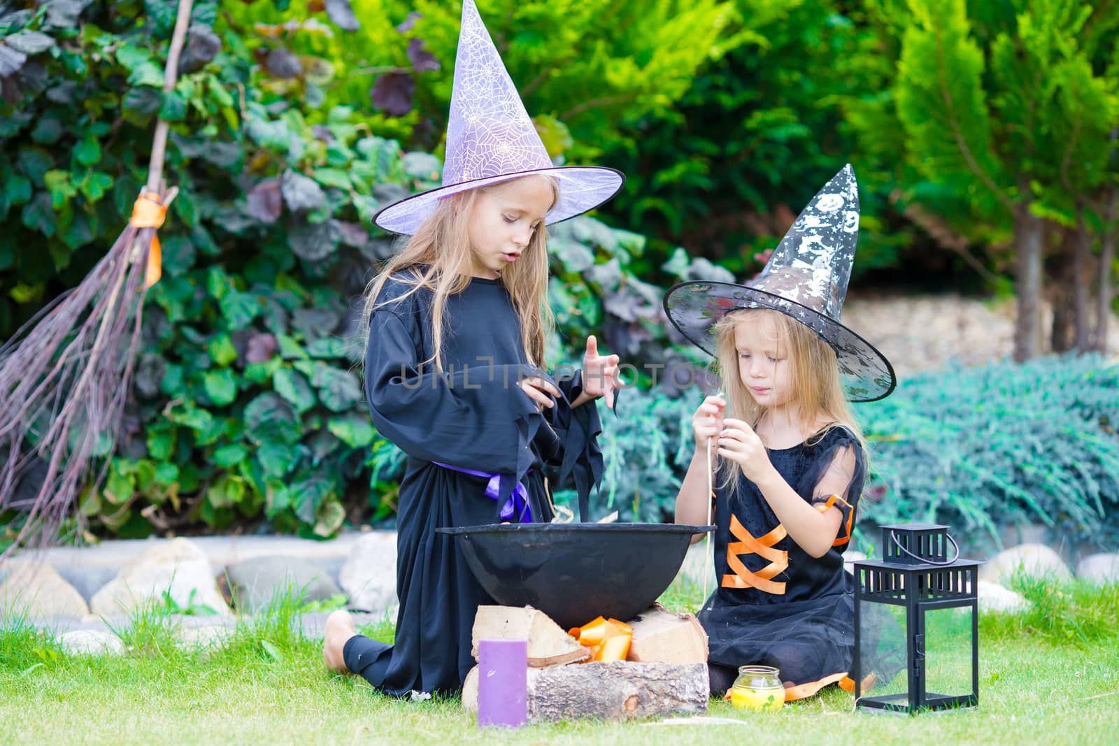 Happy little witches have fun outdoors on Halloween. Trick or treat. by travnikovstudio