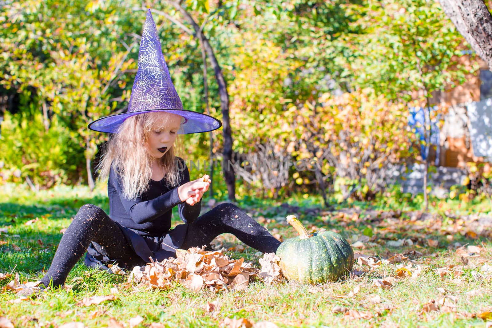 Happy little witch have fun outdoors on Halloween. Trick or treat. by travnikovstudio