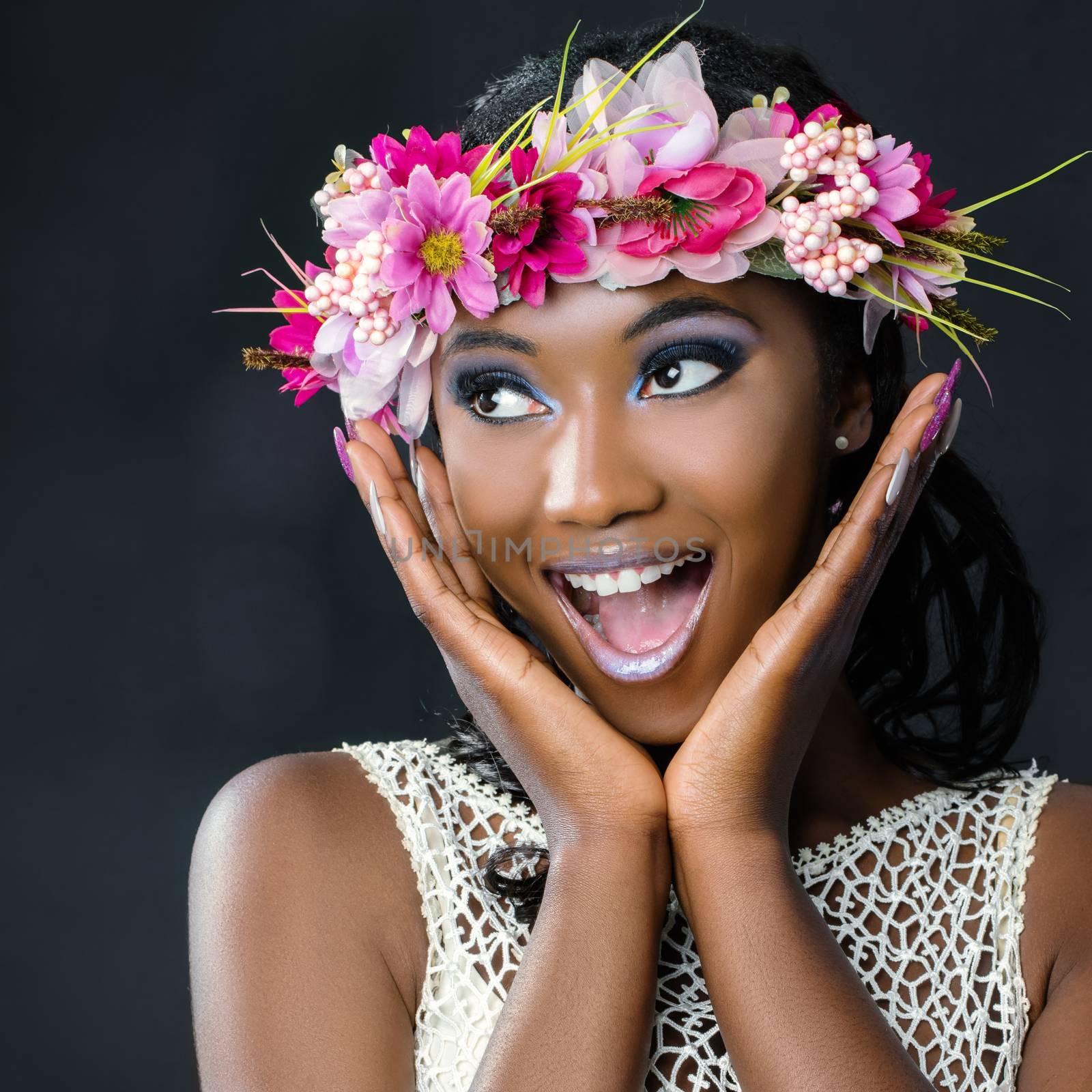 Close up fun portrait of attractive young african bride wearing colorful flower garland.Girl pulling funny face with hands next to face looking at corner.