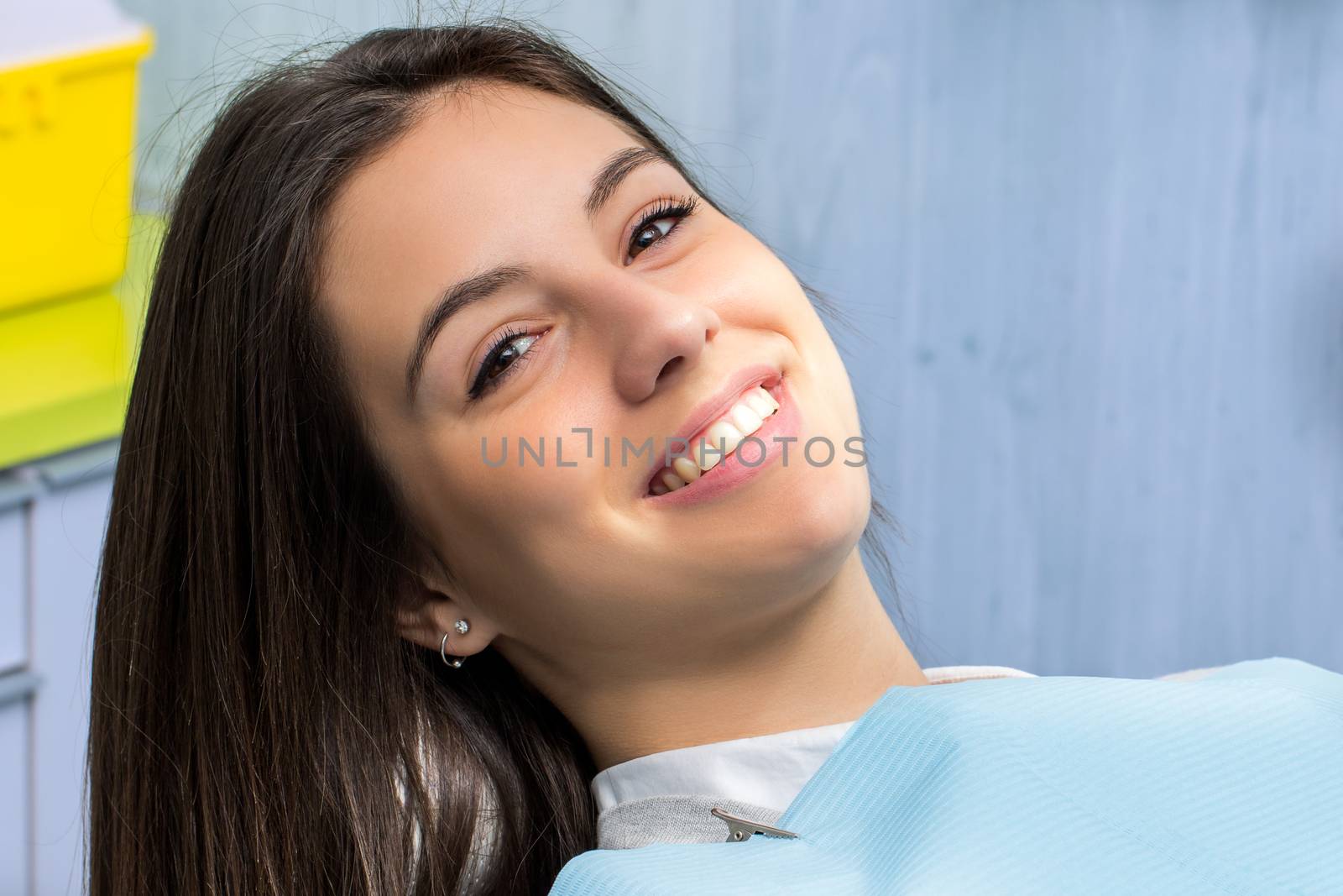 Close up portrait of cute young girl at appointment in dental clinic.Woman showing healthy teeth with captivating smile.