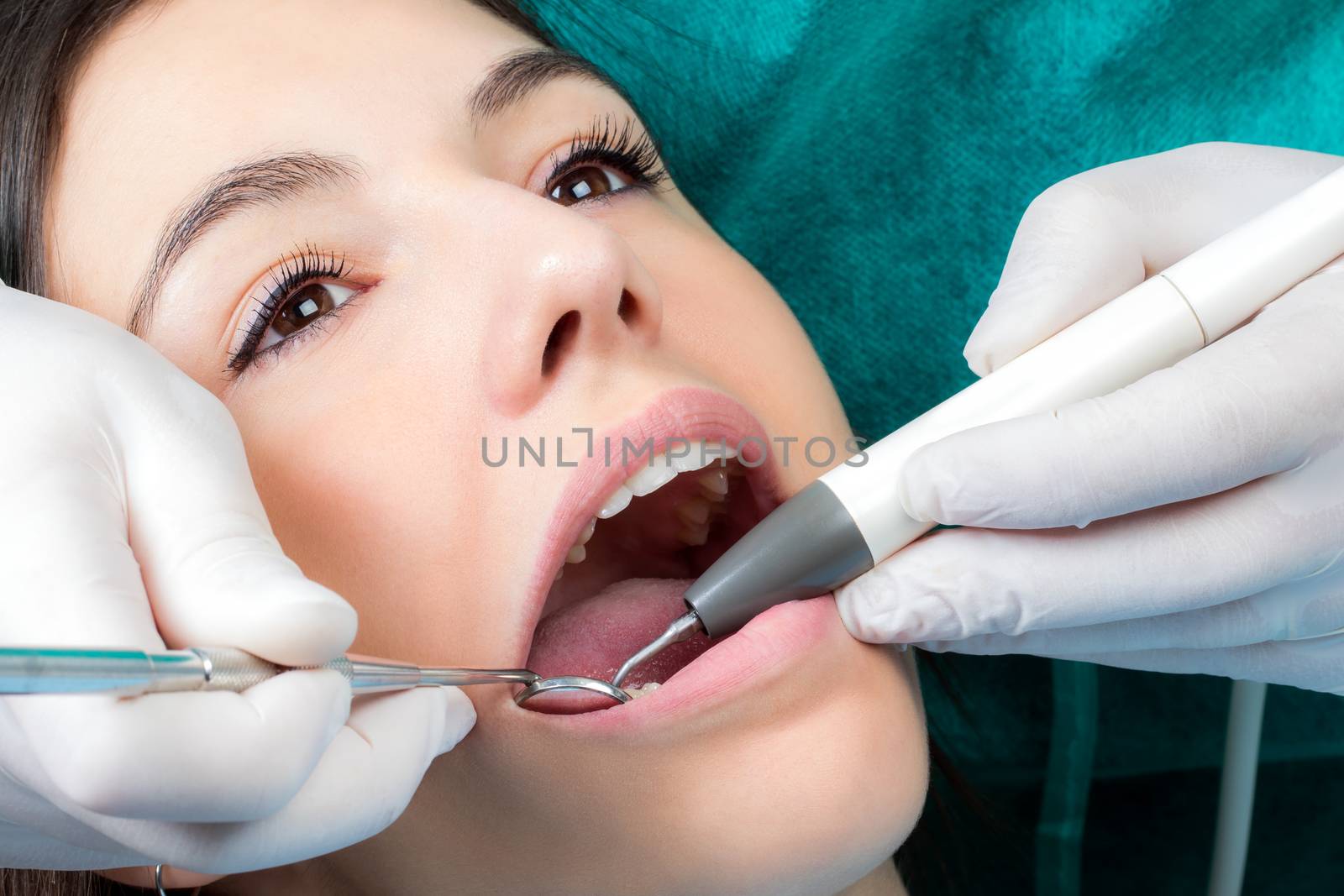 Dental hygienist cleaning girls teeth. by karelnoppe