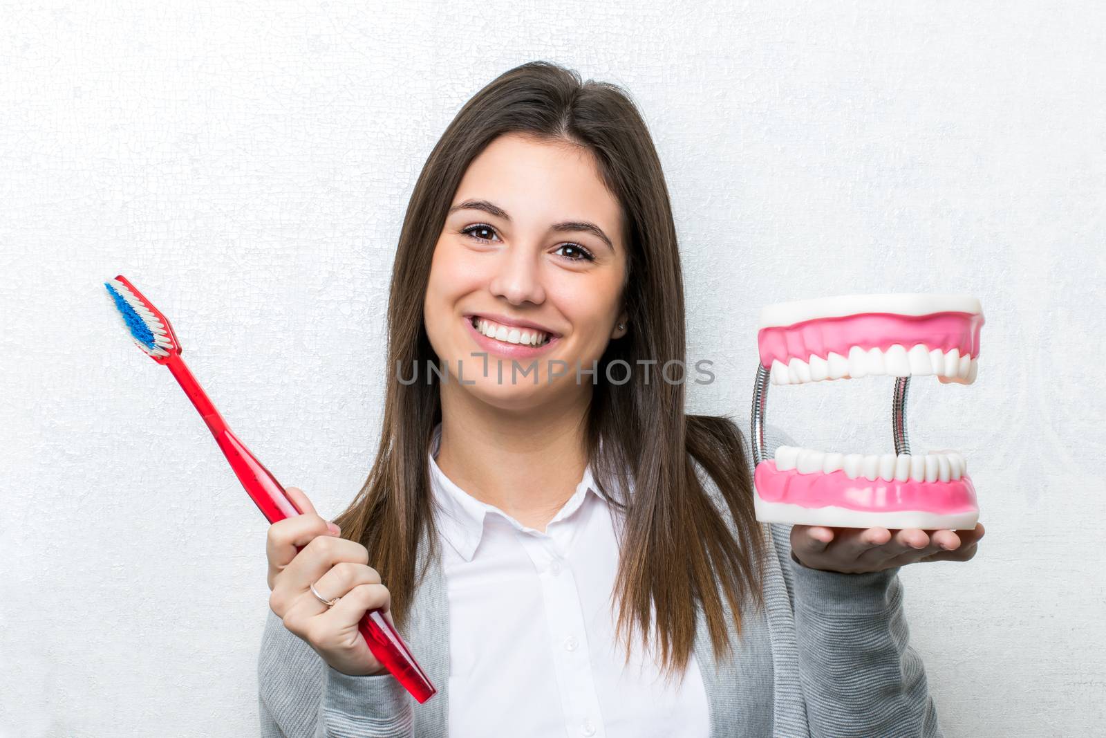 Cute girl holding oversize toothbrush and teeth prosthesis. by karelnoppe