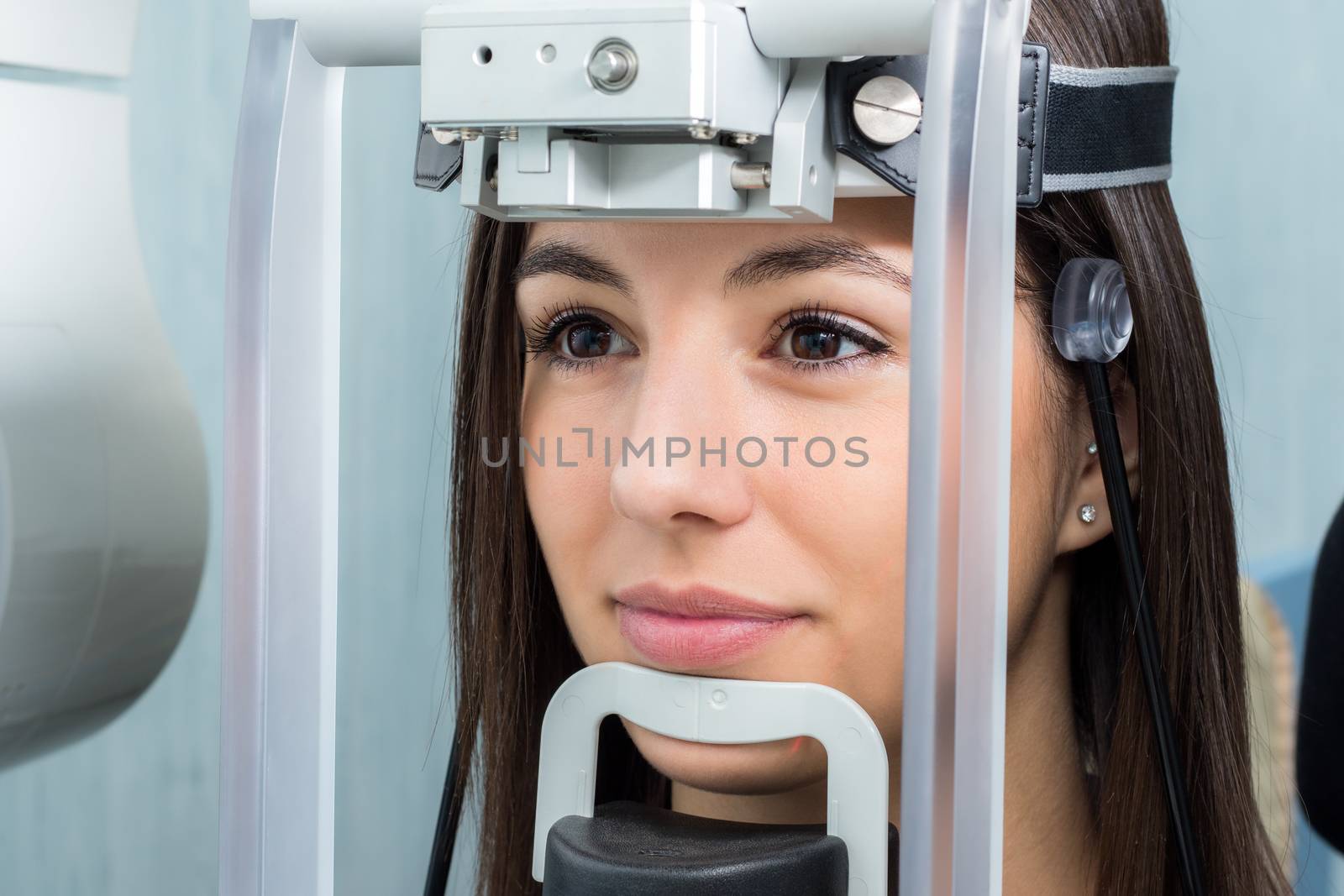 Close up face shot of girl with head positioned in cephalometric panorama x-ray machine.
