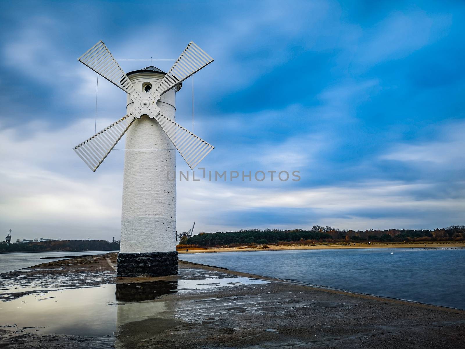 White Windmill at end of coast full of puddles near Baltic sea in Swinoujscie by Wierzchu