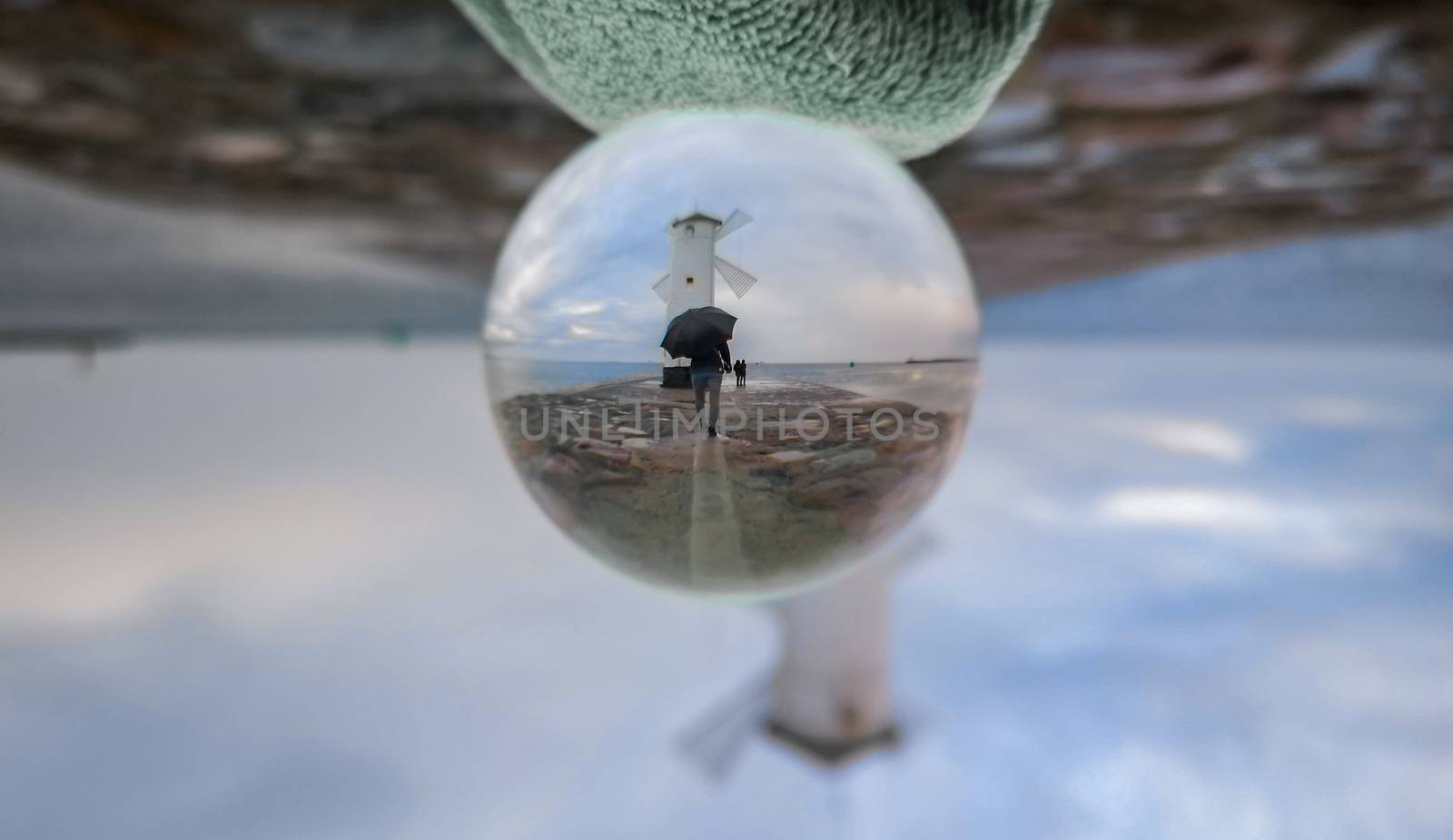 White Windmill at end of coast full of puddles near Baltic sea in Swinoujscie in reflection of crystal ball by Wierzchu