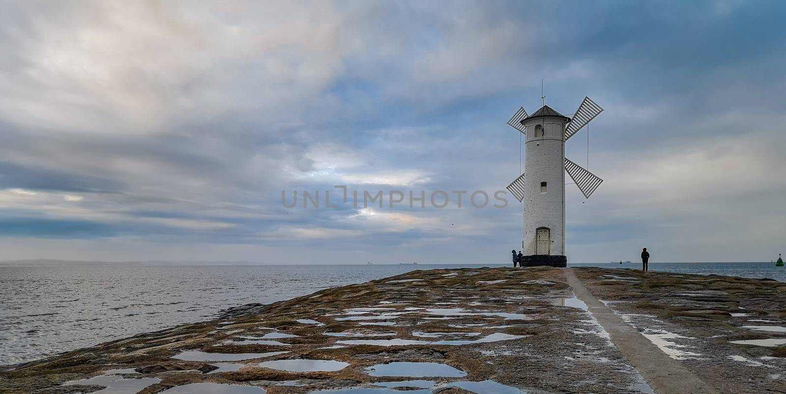 White Windmill at end of coast full of puddles near Baltic sea in Swinoujscie by Wierzchu