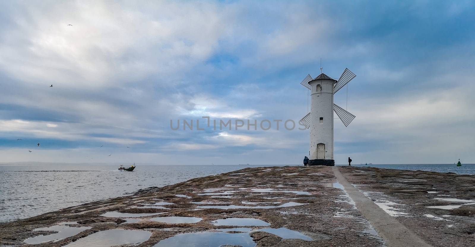 White Windmill at end of coast full of puddles near Baltic sea in Swinoujscie by Wierzchu