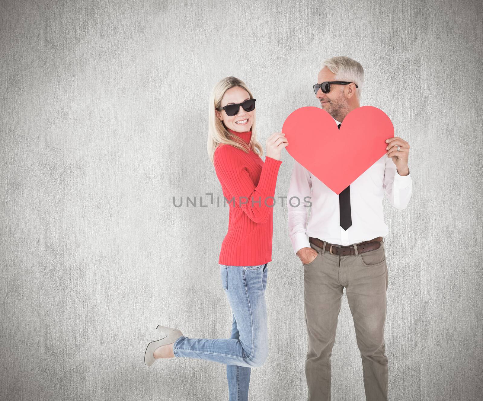 Cool couple holding a red heart together against weathered surface 
