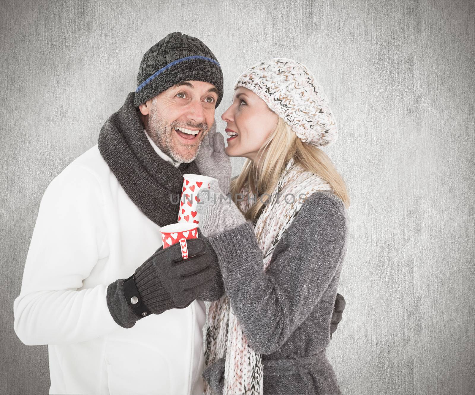 Composite image of happy couple in winter fashion holding mugs by Wavebreakmedia