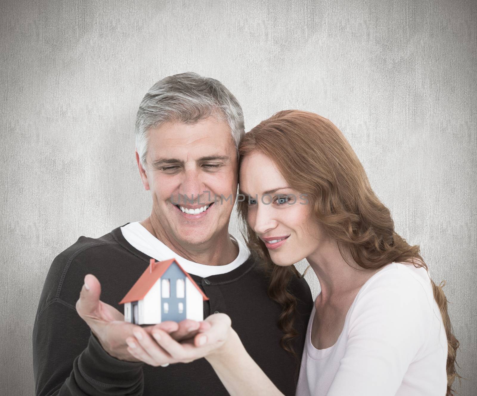 Casual couple holding small house against white background
