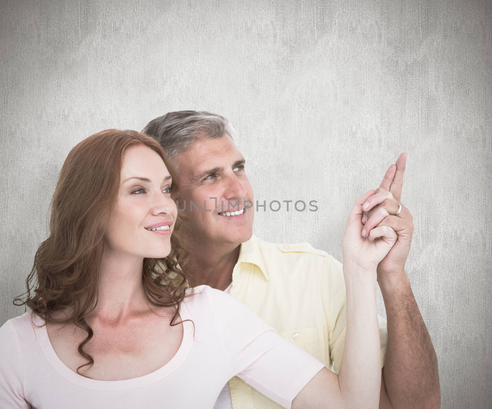 Composite image of casual couple smiling and pointing by Wavebreakmedia
