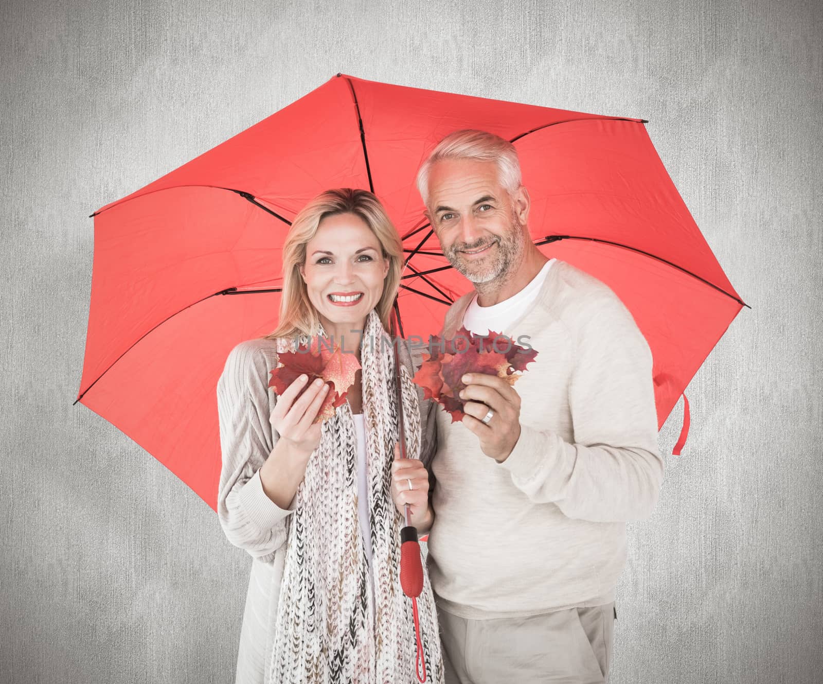 Smiling couple showing autumn leaves under umbrella against white background