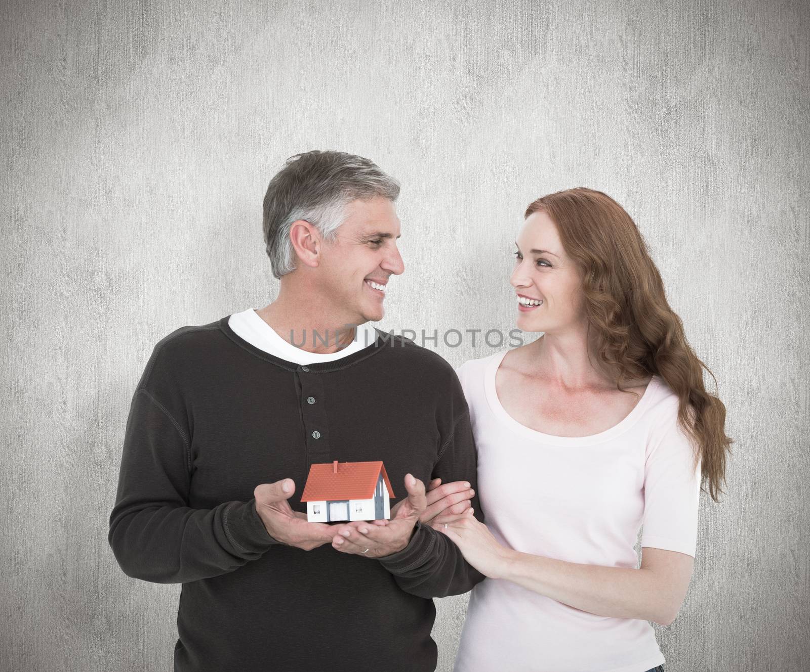 Casual couple holding small house against white background