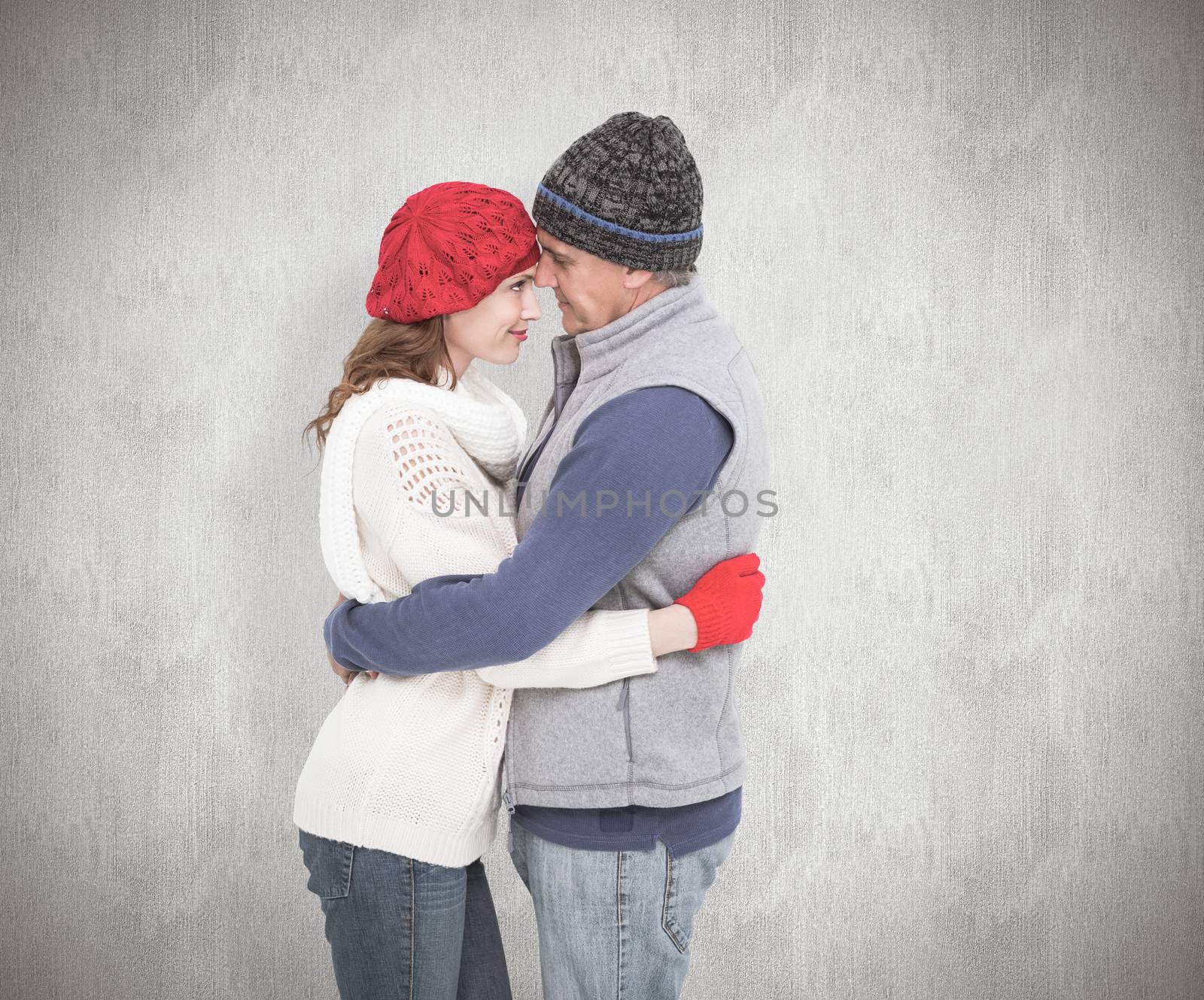 Happy couple in warm clothing hugging against white background