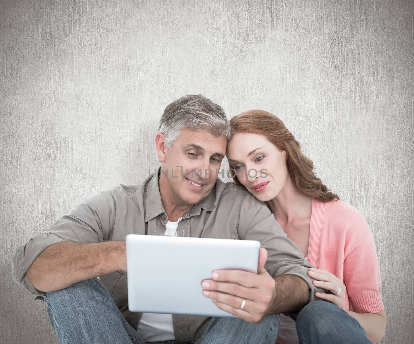 Composite image of casual couple sitting using tablet by Wavebreakmedia