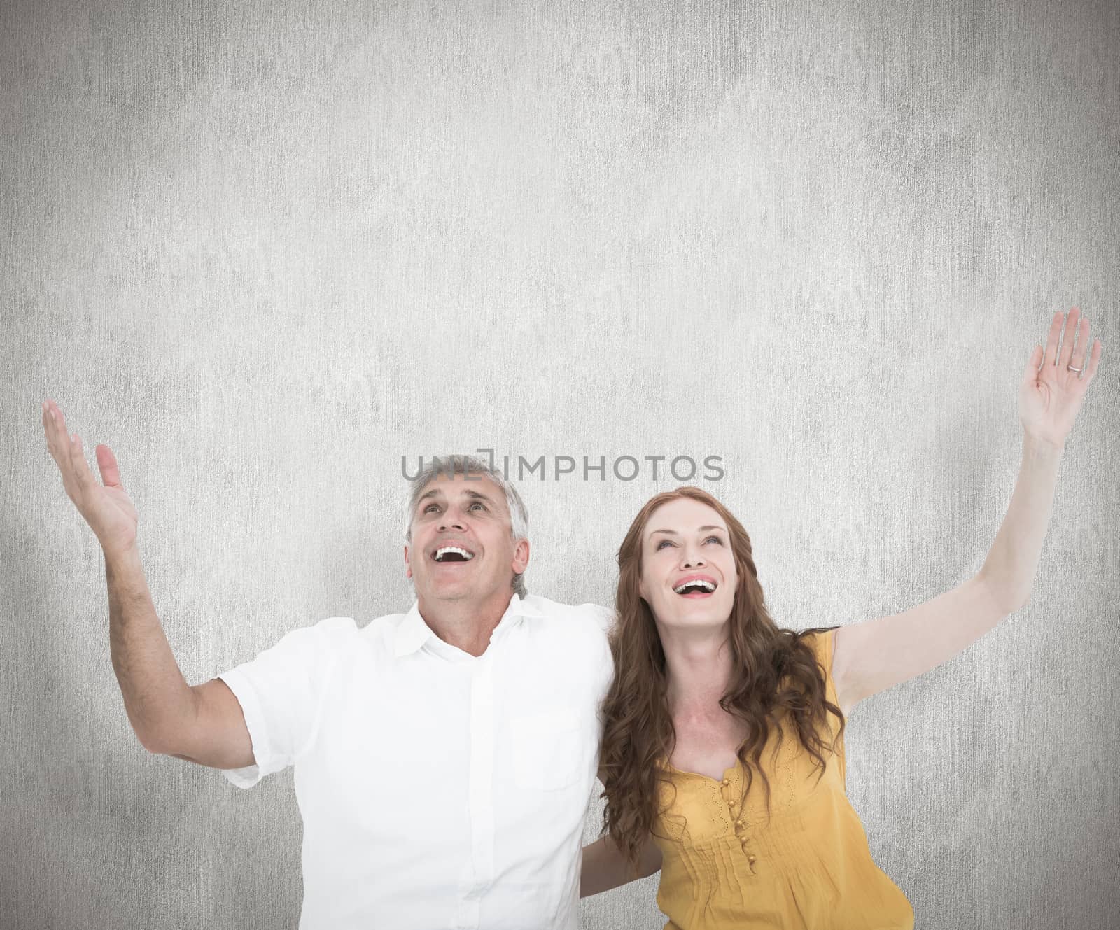 Casual couple smiling with arms raised against white background