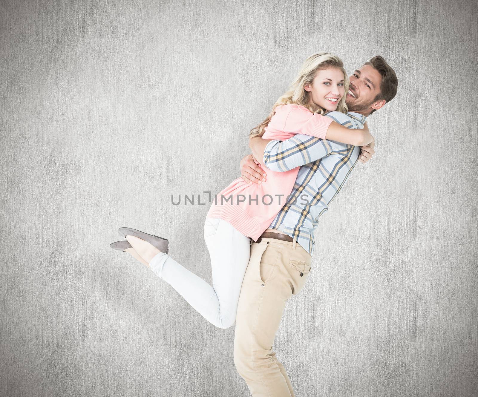 Handsome man picking up and hugging his girlfriend against white background